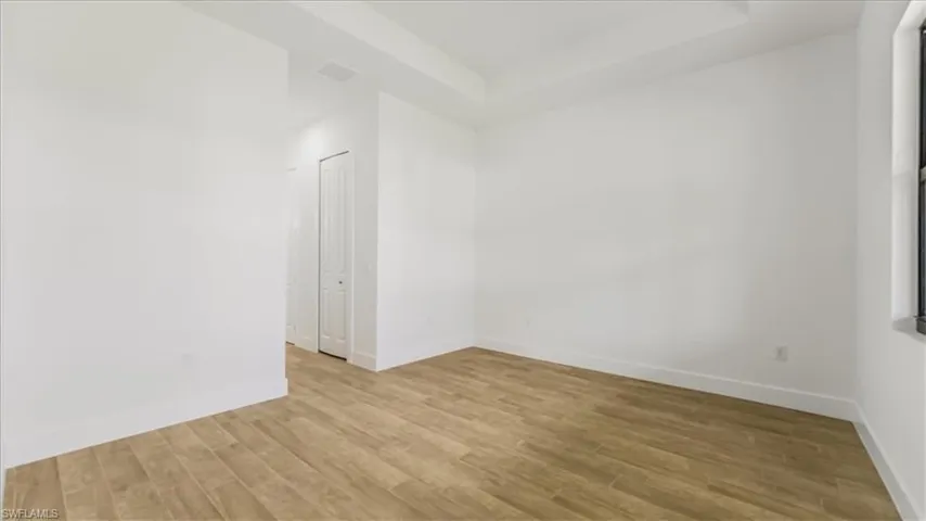Empty room with a tray ceiling and light wood finished floors