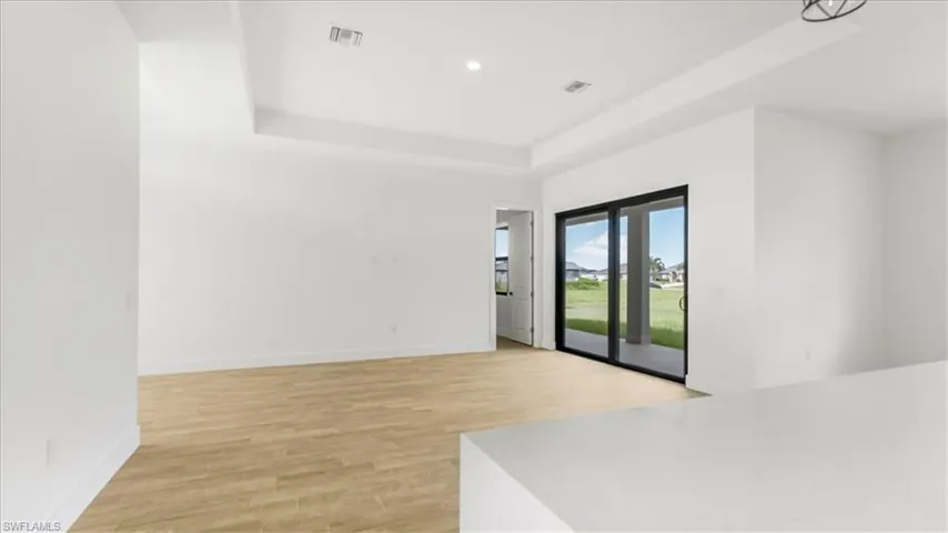 Unfurnished room with light wood-style floors, a raised ceiling, and recessed lighting