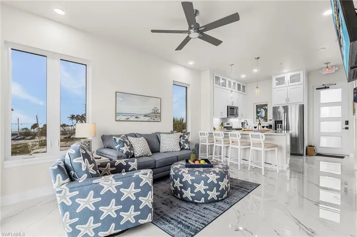 Open concept living area featuring high ceilings, recessed lighting, and large windows - Virtually Edited Image