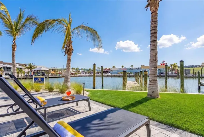 Waterfront patio with paver surfacing, featuring an adjacent lawn and tropical landscaping - Virtually Edited Image