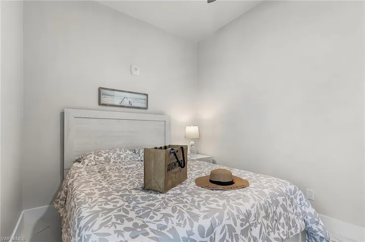 Bedroom featuring a light wood-finish headboard, neutral wall paint, and white baseboards - Virtually Edited Image