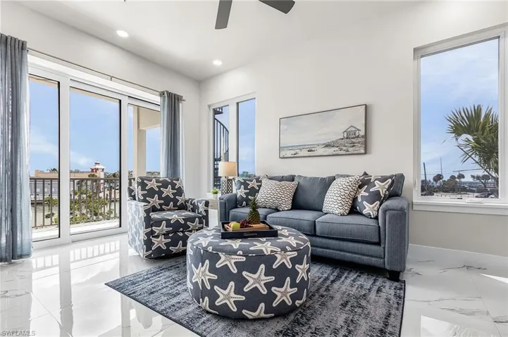 Spacious living area featuring polished tile flooring, abundant natural light from large windows, and direct access to an outdoor balcony - Virtually Edited Image