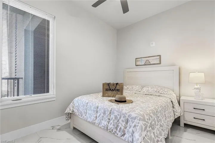 Bedroom featuring a large window with horizontal blinds, a ceiling fan, and light-toned wall paint - Virtually Edited Image