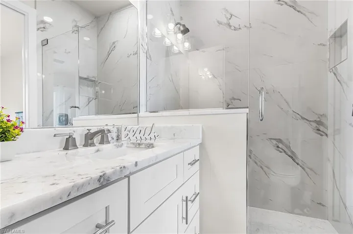 Bathroom vanity featuring a polished stone countertop, undermount sink, and brushed nickel fixtures - Virtually Edited Image