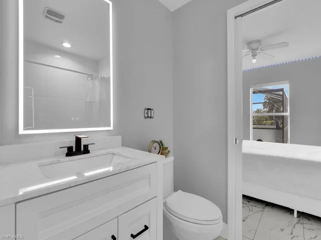 Bathroom featuring vanity, toilet, ceiling fan, and curtained shower