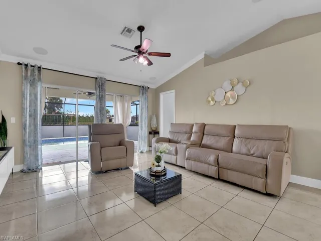Living room with ceiling fan, crown molding, light tile patterned floors, and lofted ceiling