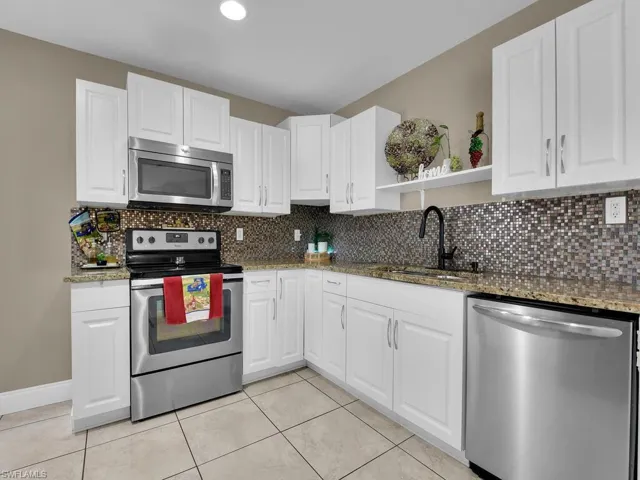Kitchen featuring sink, white cabinets, dark stone counters, and appliances with stainless steel finishes