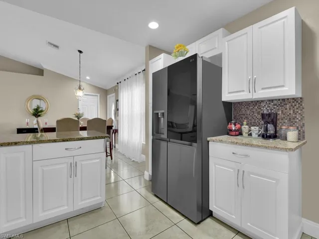 Kitchen with white cabinetry, pendant lighting, dark stone counters, and lofted ceiling