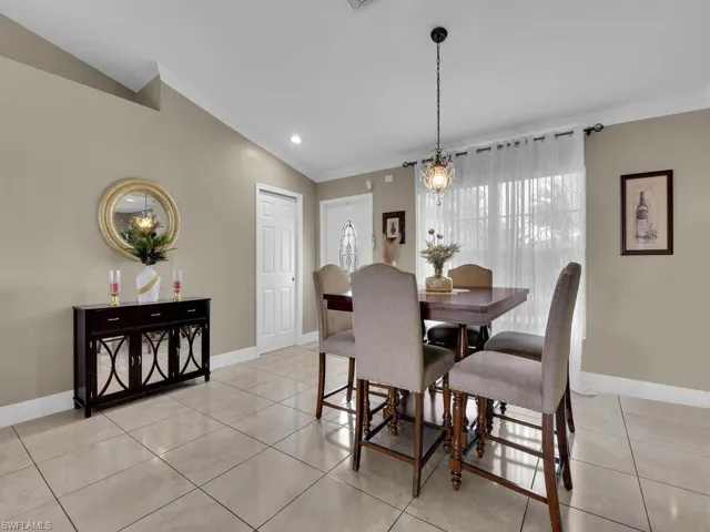 Tiled dining room with ornamental molding and lofted ceiling