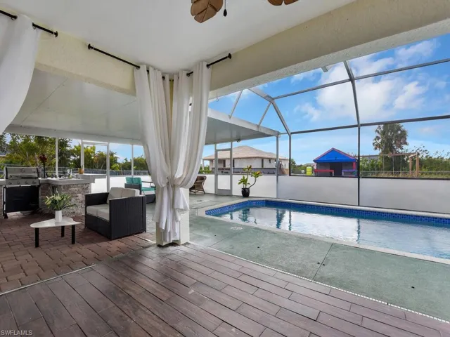 View of swimming pool featuring ceiling fan, a patio area, a bar, and area for grilling