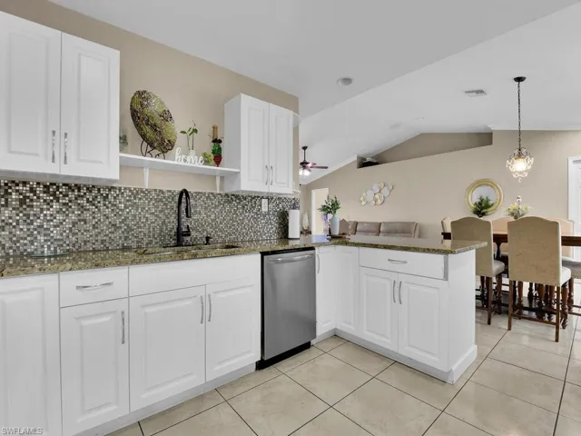 Kitchen featuring sink, dark stone counters, kitchen peninsula, and stainless steel dishwasher