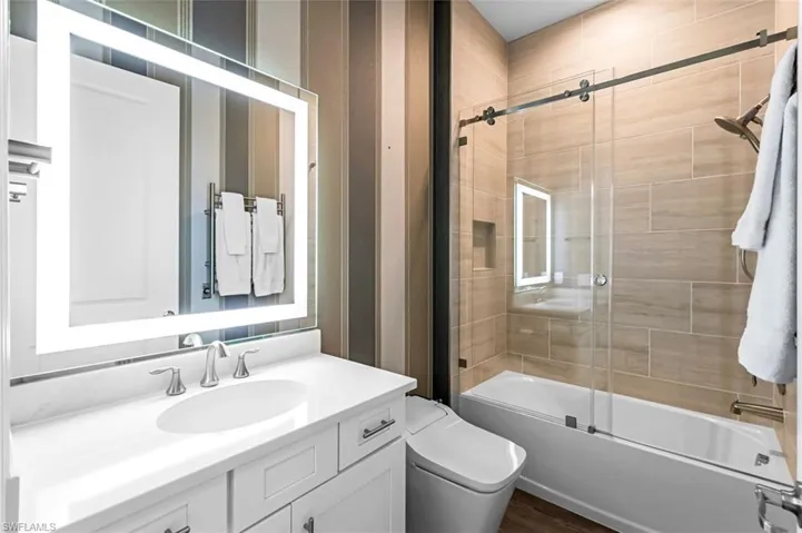 Full bathroom with vanity with extensive cabinet space, toilet, and enclosed tub / shower combo