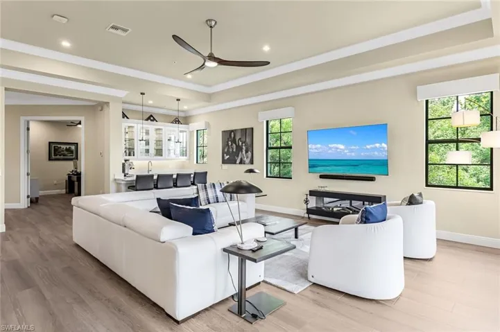 Living room with a tray ceiling, ceiling fan, and light hardwood / wood-style flooring