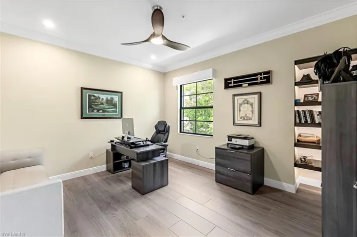 Office/Den with crown molding, ceiling fan, and wood-look tile floors. Lutron lighting, fan, shades & lighted shelves.