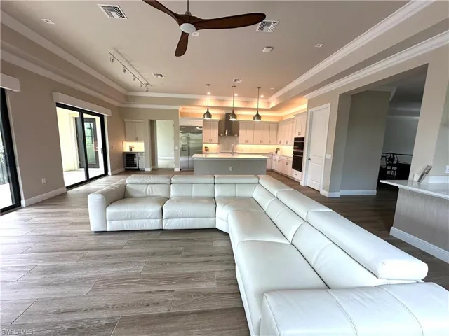 Living room with ornamental molding, hardwood / wood-style flooring, rail lighting, and ceiling fan