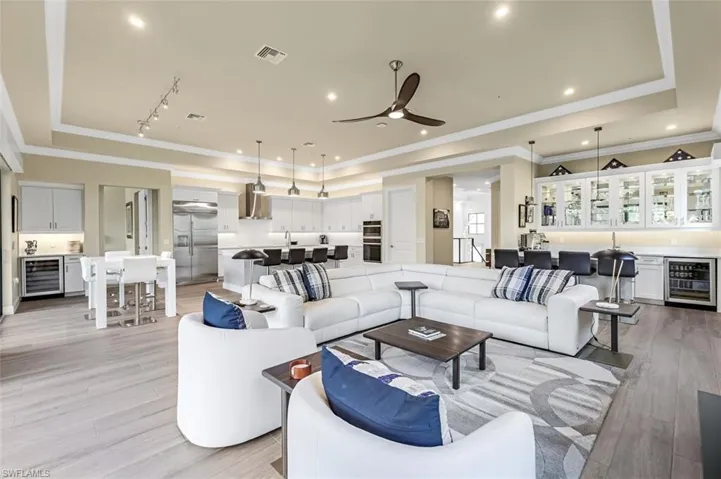 Living room featuring beverage cooler, light hardwood / wood-style flooring, and a raised ceiling