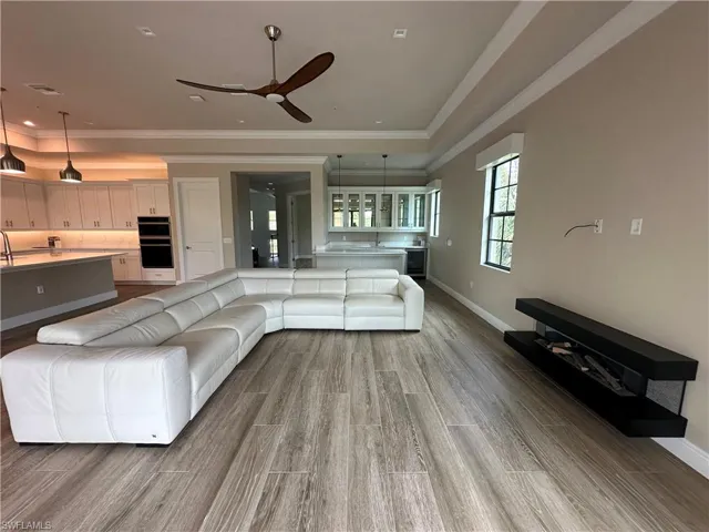 Unfurnished living room with ornamental molding, sink, light wood-type flooring, and ceiling fan