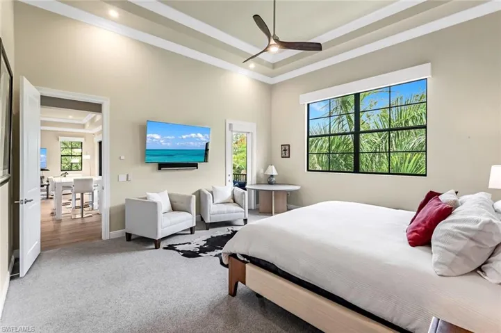 Primary BR w/carpeted bedroom featuring ceiling fan, a tray ceiling, and crown molding