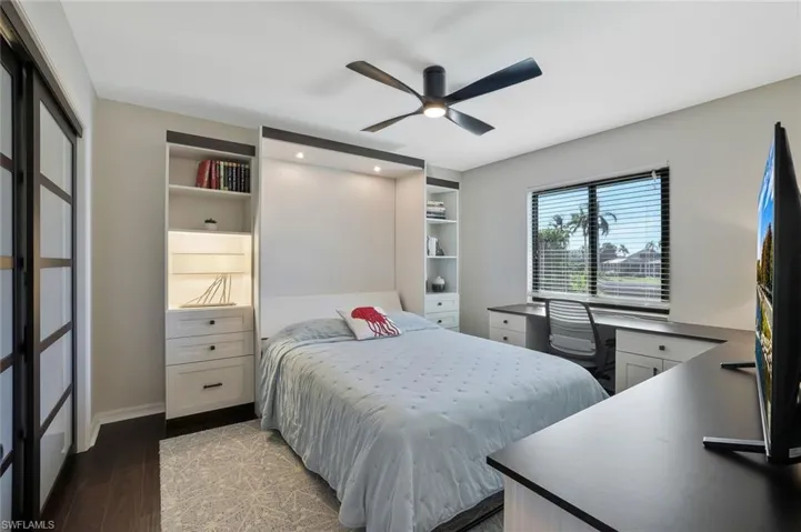 Bedroom featuring dark wood-style floors, a ceiling fan, and an office area