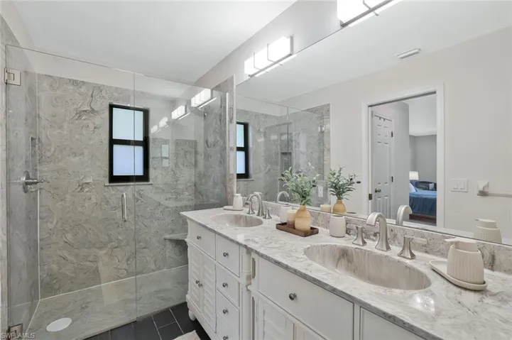 Ensuite bathroom featuring double vanity and a marble finish shower