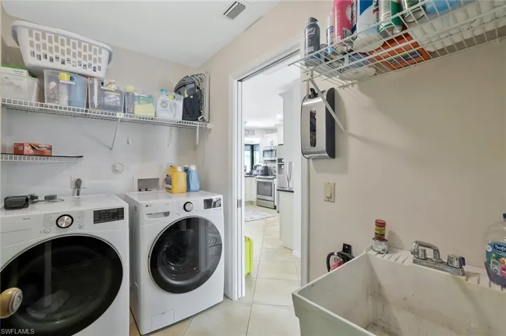 Laundry room with independent washer and dryer and light tile patterned floors