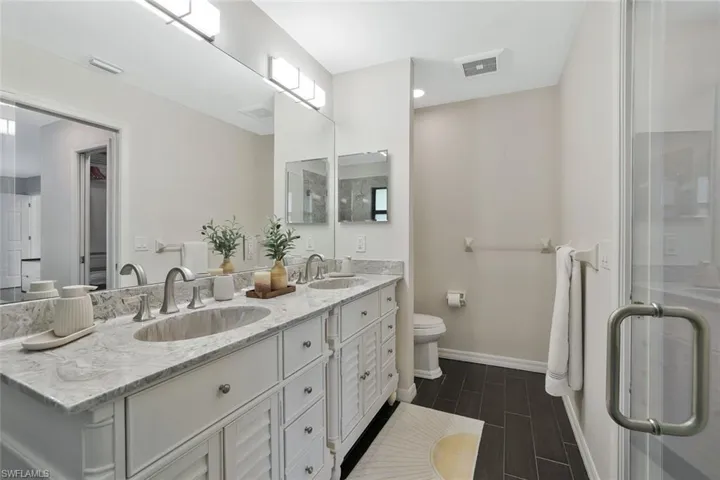 Bathroom with double vanity, wood tiled floors, and a shower stall