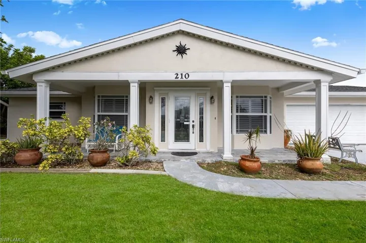 View of front facade with an attached garage, stucco siding, a front lawn, and covered porch