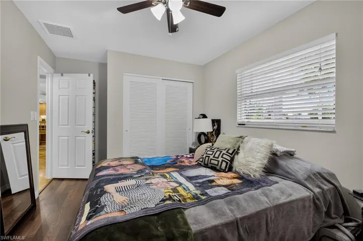 Bedroom featuring dark wood-style flooring, a closet, and a ceiling fan