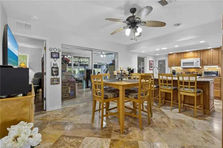 Dining room with ceiling fan, light stone finish floors, and recessed lighting
