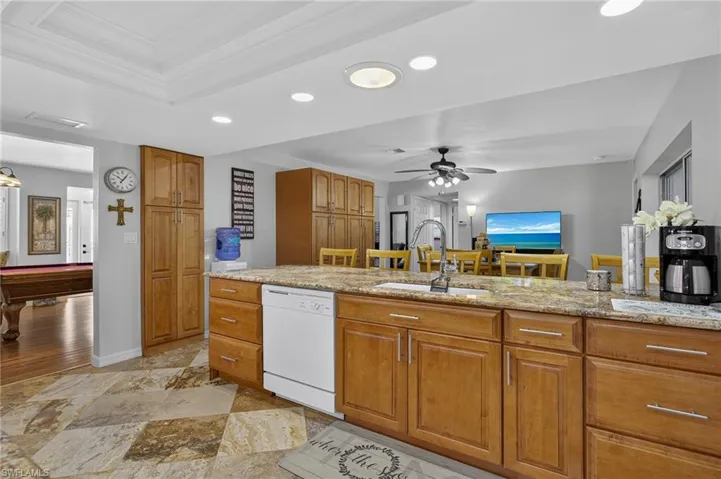 Kitchen featuring white dishwasher, brown cabinetry, crown molding, a ceiling fan, and recessed lighting