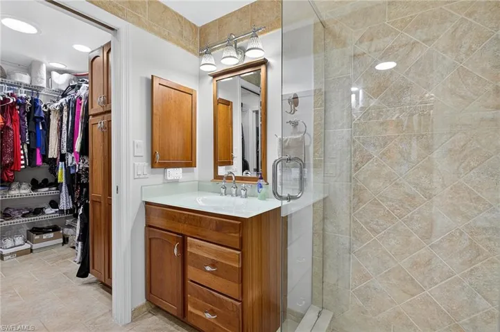 Bathroom with vanity, a stall shower, and a spacious closet