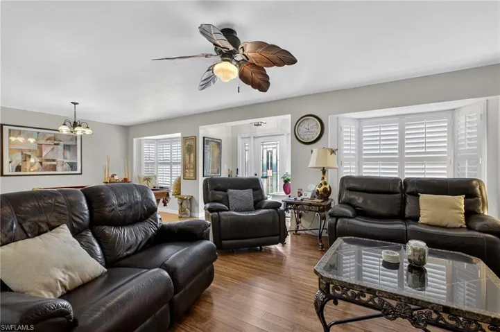 Living area featuring ceiling fan, wood finished floors, and a chandelier