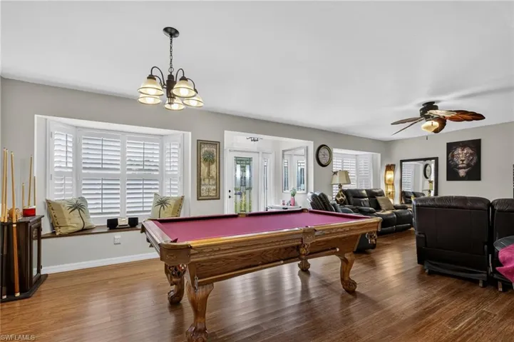 Rec room featuring wood finished floors, billiards table, a ceiling fan, and a chandelier