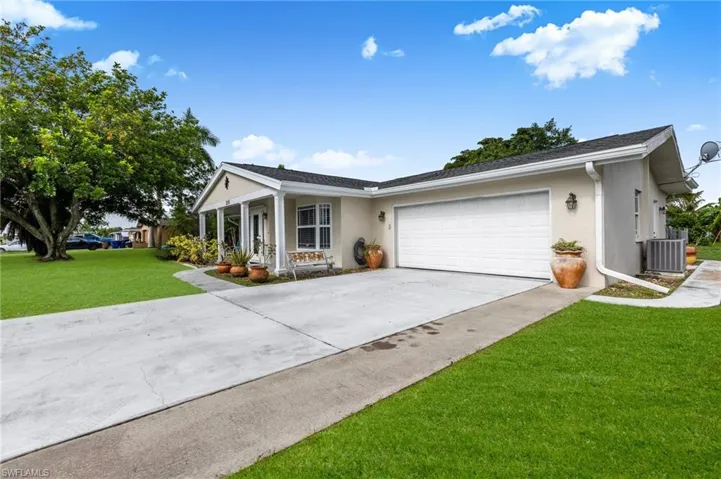 Ranch-style home with concrete driveway, a garage, a front yard, stucco siding, and a porch