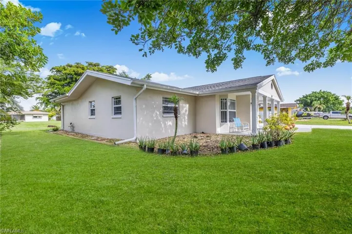 View of side of home with stucco siding and a yard