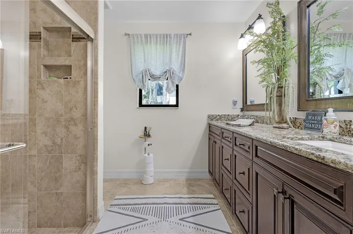 Guest bathroom close proximity to Bedrooms 3 & 4, featuring baseboards, double vanity, and a shower stall overlooking north side yard