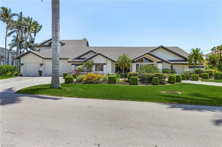 View of front of property featuring a tiled roof, driveway, a front yard, a garage, and stucco siding