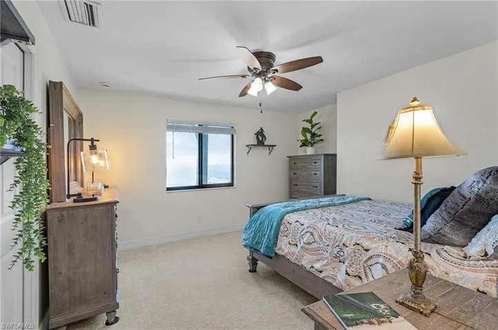 Bedroom # 3 featuring baseboards, light colored carpet, ceiling fan, River view and walk in closet