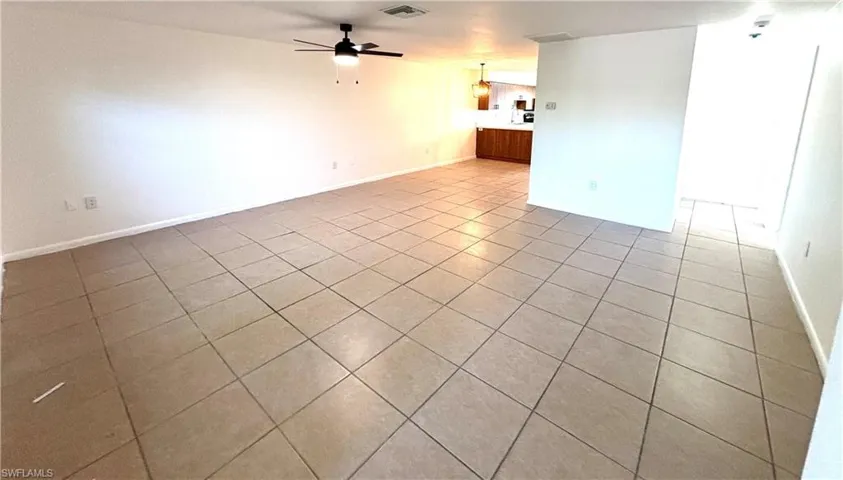 Tiled empty room featuring baseboards and a ceiling fan