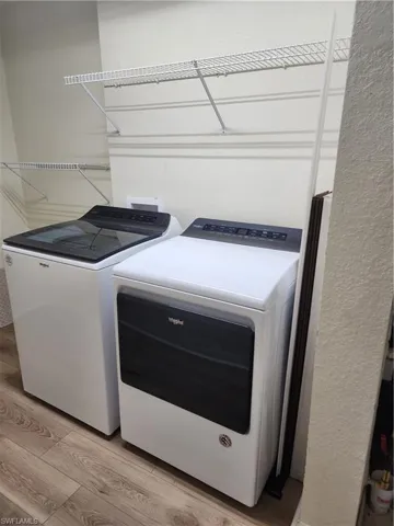 Washroom with light wood-style flooring and separate washer and dryer
