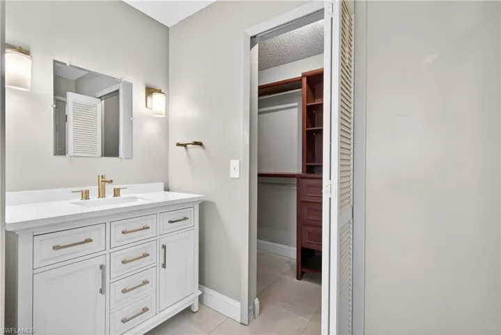 Bathroom vanity featuring a white countertop with an integrated sink and brass-finish faucet