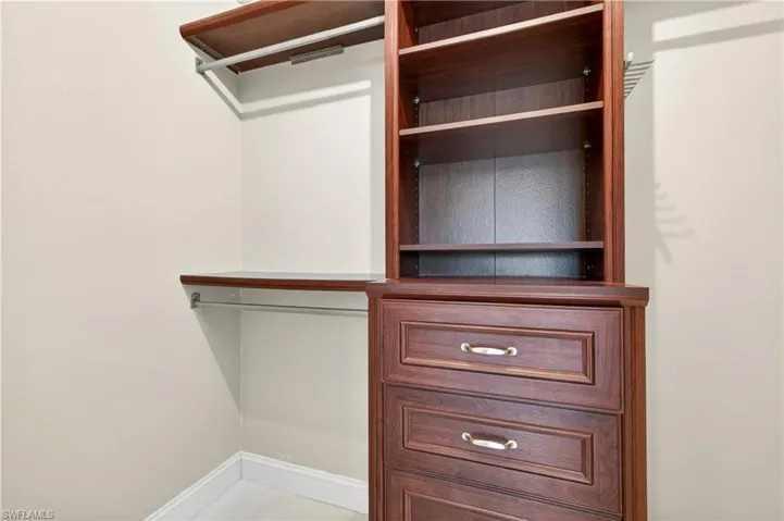 Custom wood-finish closet system featuring integrated shelving, multiple drawers with polished nickel hardware, and dual hanging rods