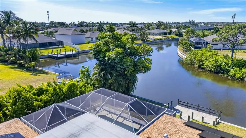 Waterfront property featuring a private boat dock, screened enclosure, and mature landscaping