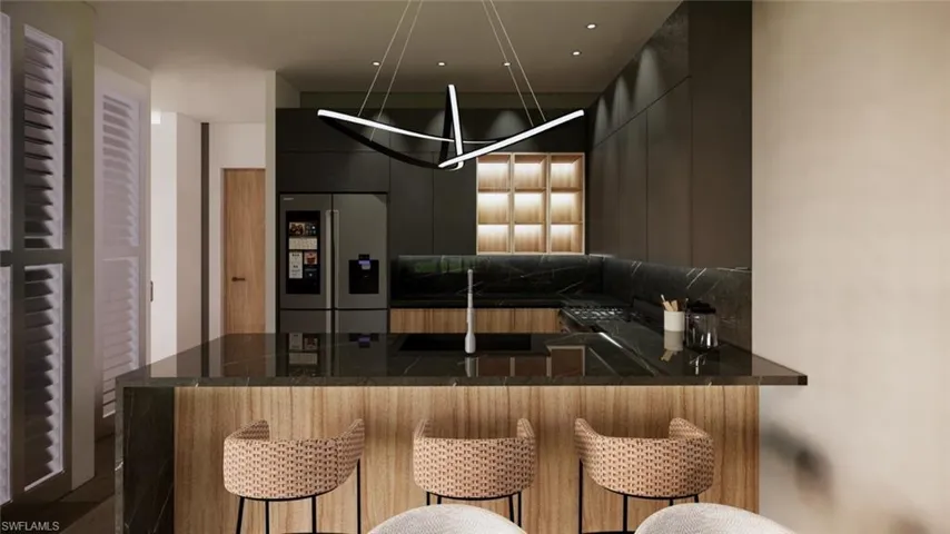 Kitchen featuring modern cabinets, stainless steel fridge, a kitchen bar, a peninsula, and dark stone countertops