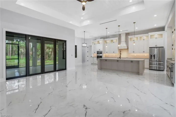 Kitchen with appliances with stainless steel finishes, custom range hood, a center island with sink.