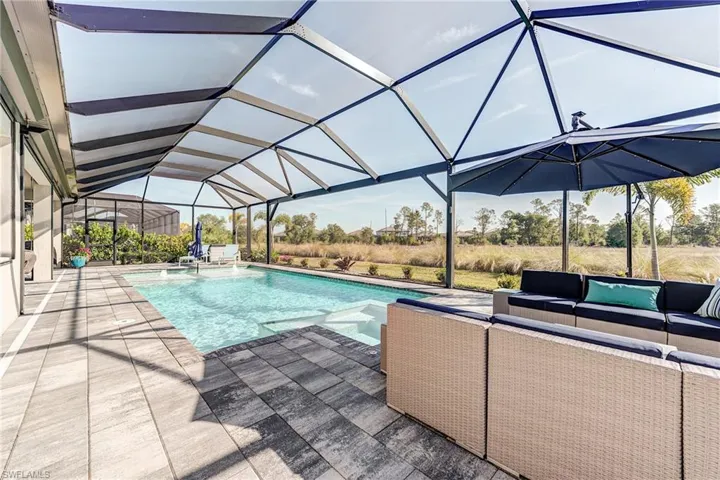 Pool with screen enclosure, a patio, and an outdoor hangout area