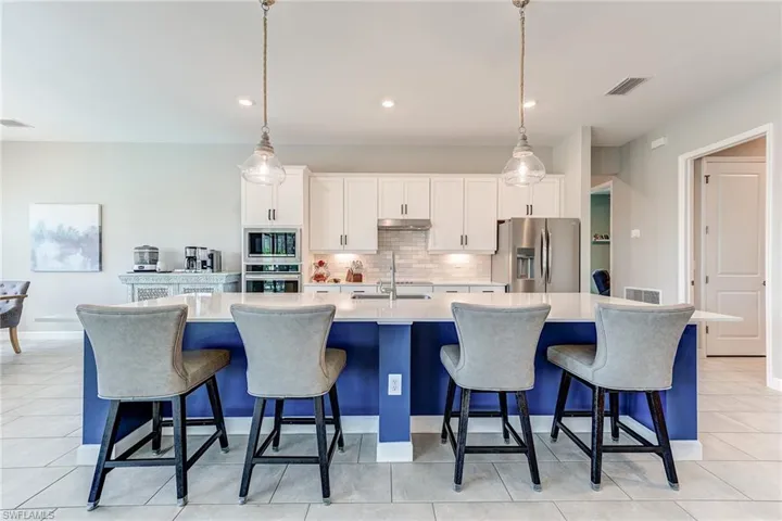 Kitchen featuring under cabinet range hood, visible vents, a spacious island, and stainless steel appliances