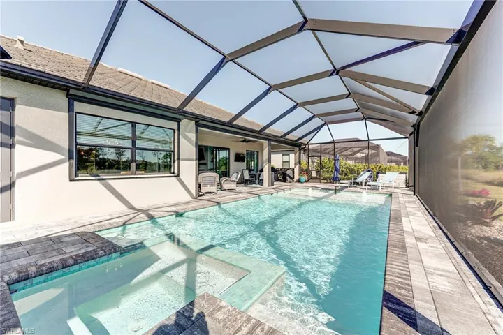 Pool with a patio area, screen enclosure, a jacuzzi, and a ceiling fan