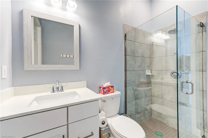 Full bath featuring quartz countertops and seamless glass shower door
