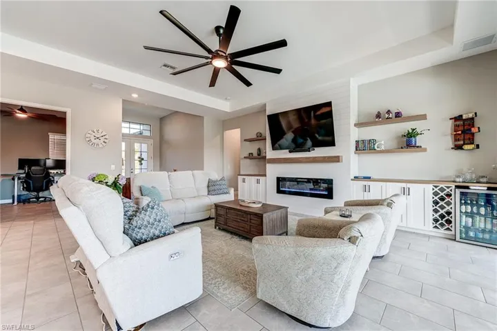 Living area with wine cooler, visible vents, a large fireplace, and ceiling fan